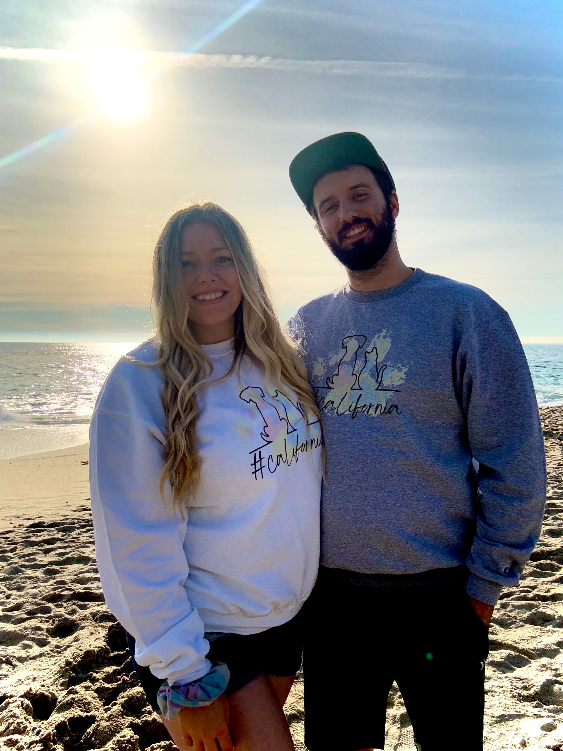 Couple on the beach showcasing their new California pet parent sweatshirts